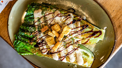 Tazón de ensalada con lechuga, pollo a la parrilla, crutones y aderezo por encima.
