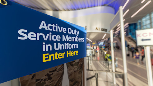 Sign directing active duty service members in uniform to enter at airport security checkpoint.