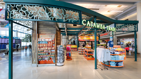 Catawba Trade airport shop with snacks, drinks, and apparel displayed under a decorative green archway.