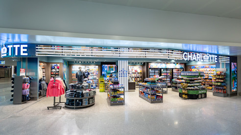 Tienda minorista en el aeropuerto de Charlotte que vende recuerdos, bocadillos, ropa y artículos de viaje, con estantes y exhibidores organizados.