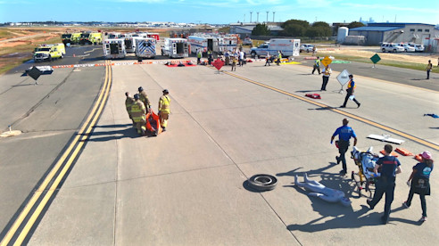 Equipos de respuesta a emergencias realizan un ejercicio de entrenamiento en una pista del aeropuerto con vehículos y equipo.