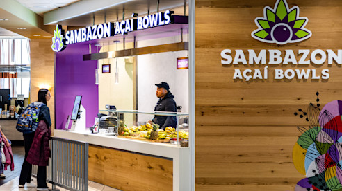 Sambazon Açaí Bowls restaurant at an airport with customers ordering at the counter.