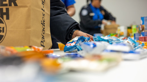 Voluntarios organizan donaciones de refrigerios en una mesa durante una colecta comunitaria de alimentos.