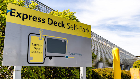 Express Deck Self-Park sign showing a map and “You are here” marker near an airport parking facility.