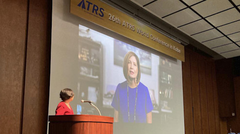 Speaker presents via video screen at a conference podium during the ATRS virtual conference.