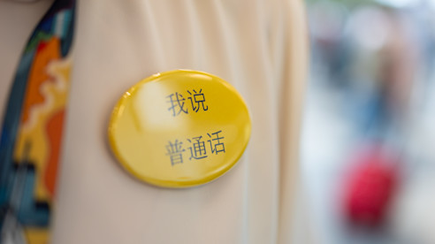 Botón amarillo que dice “Hablo mandarín” en chino, colocado en una chaqueta.