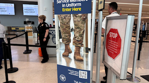 Sign for active duty service members in uniform to enter TSA PreCheck lane at airport security.