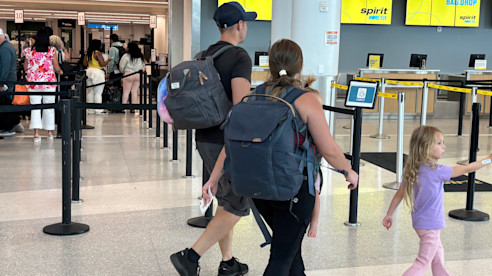 Family walking through airport near Spirit check-in and bag drop area.