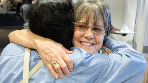 Janice Futrell smiles while hugging a guest. 