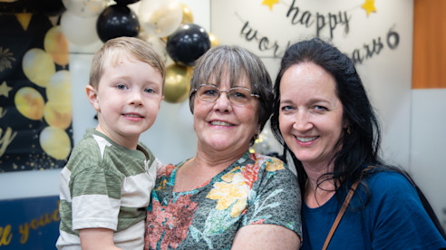 Janice Futrell poses smiling with a child and a woman during her 50-year anniversary celebration.