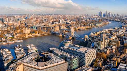 Aerial view of London with the River Thames, Tower Bridge, and city skyline in the distance.