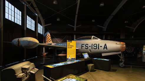 Avión antiguo de la Guardia Nacional Aérea con paneles informativos y cola con rayas de tigre.