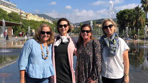 Four women standing together outdoors on a sunny day.