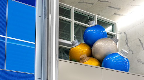 Blue, gold, and silver ornament decorations displayed on a ledge near a wall and window.