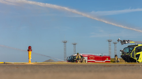 Bomberos y vehículos de emergencia ubicados en una pista del aeropuerto durante un ejercicio de entrenamiento.