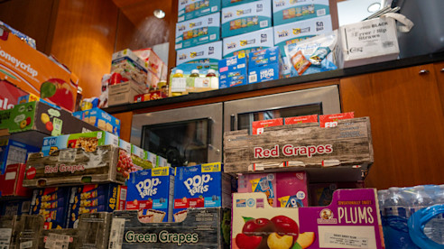  Boxes of snacks, fruit, and drinks are stacked in a USO center, ready for distribution to visitors.